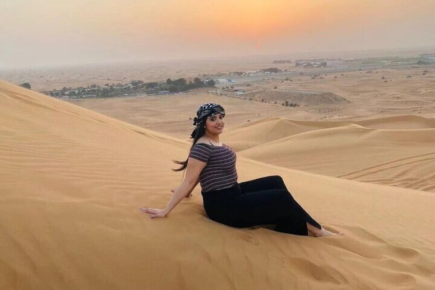 A person sitting on a sand dune with a sunset in the background. 3