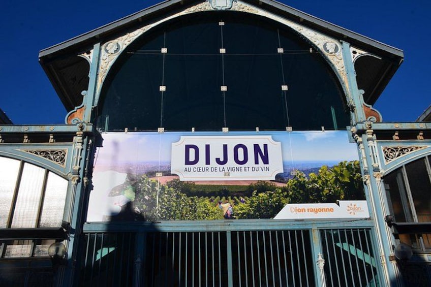 Une enseigne portant les mots « DIJON » et « AU CŒUR DE LA VIGNE ET DU VIN » est fixée à la façade d’un immeuble. 4