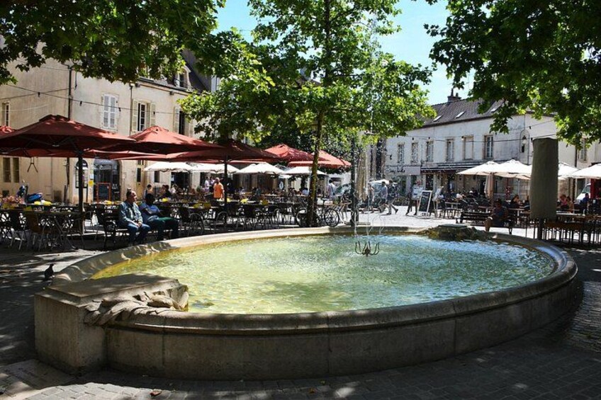 Une place publique avec une fontaine, des sièges en plein air et des arbres. 3