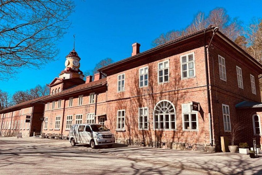 A red brick building with a clock tower, a parked car, and bare trees. 5