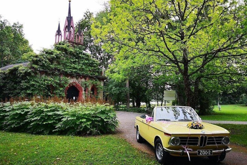 A yellow convertible car parked in front of a church with a spire. 2