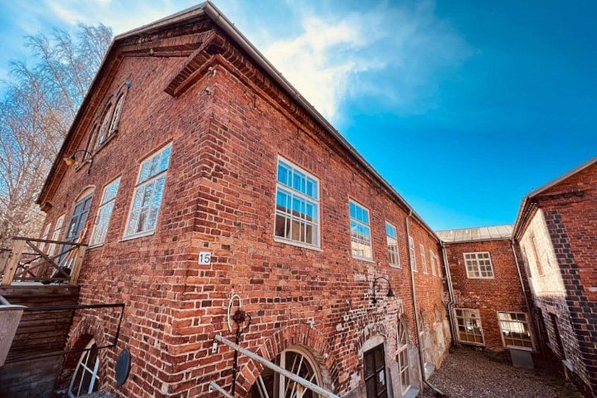 A red brick building with a number '15' on its side, a door, and a window. 1