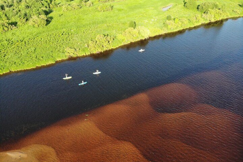 Luchtbeeld van een rivier met drie boten en een groen landschap. 1