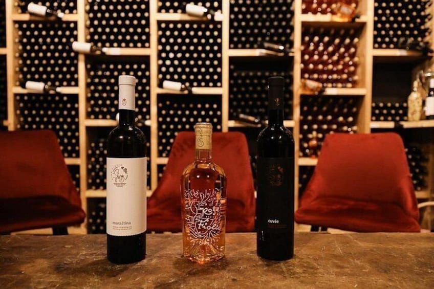 Three wine bottles on a table with a wine cellar in the background. 2
