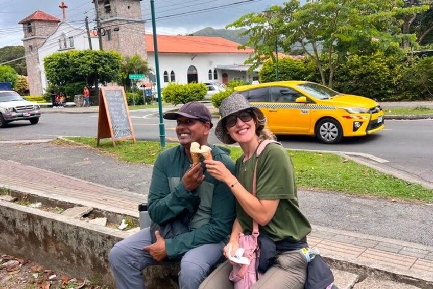 Two people sitting on a ledge, a yellow taxi, and a church in the background. 2
