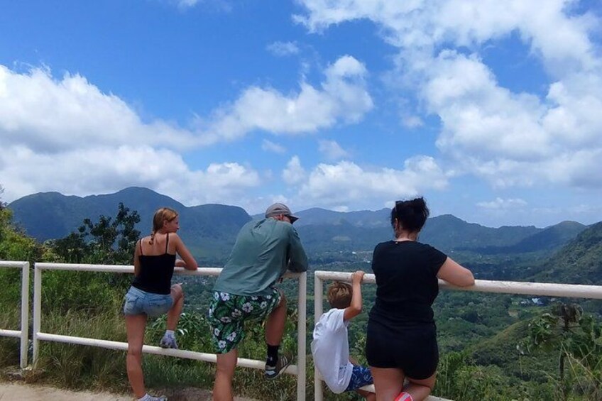 A group of people standing on a railing overlooking a mountainous landscape. 5