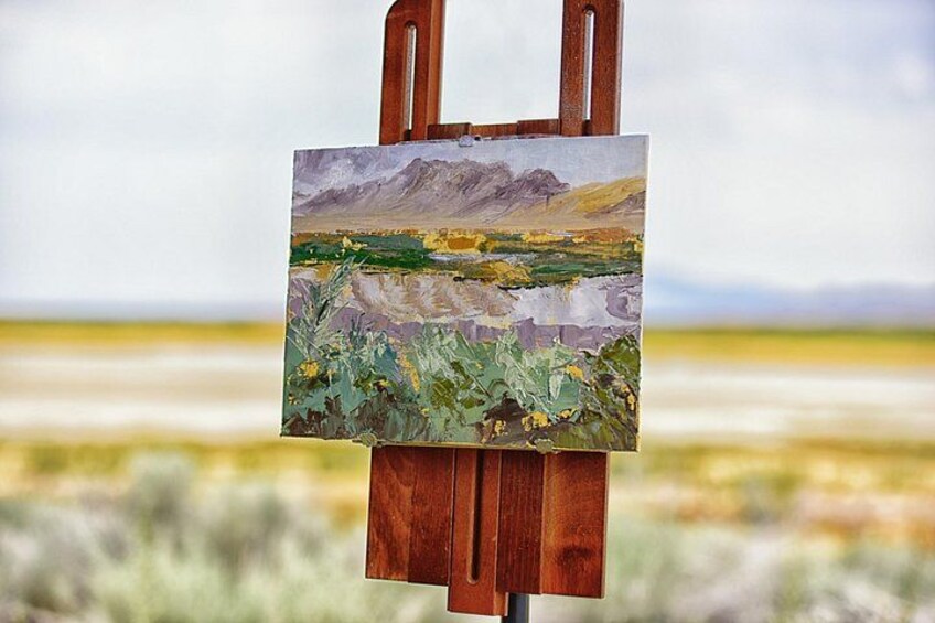 Un chevalet sur lequel est posé un tableau représentant un paysage de montagnes et un champ. 4