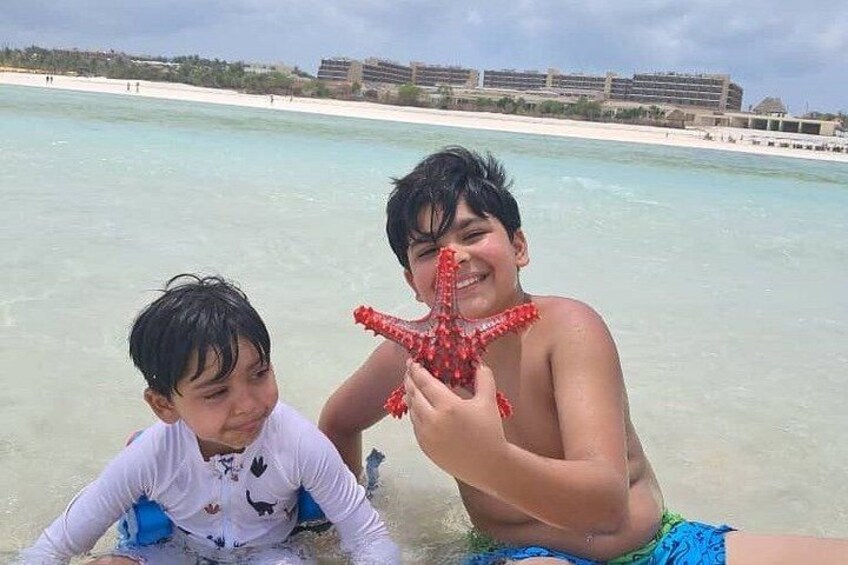 Zwei Personen an einem Strand mit klarem Wasser und einer entfernten Küste. 3