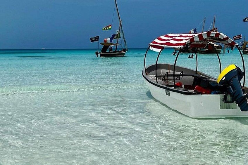 A boat with an American flag on the water, another boat with a sail, and a clear blue sea. 2