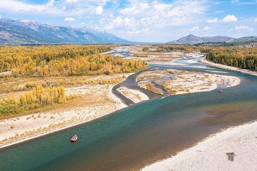 A river meandering through a forest with autumn foliage, surrounded by mountains. 1