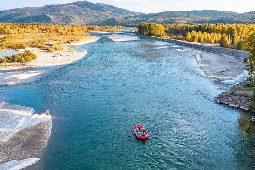 A river with a red boat, surrounded by autumn-colored trees and distant mountains. 5