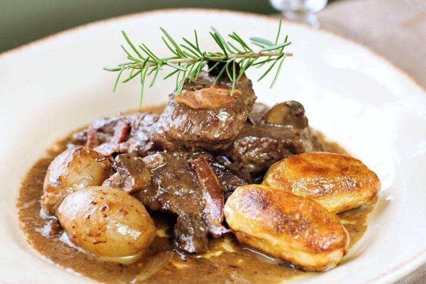 A plate of beef stew with potatoes and a sprig of rosemary. 4