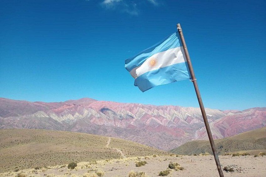 Ein Fahnenmast mit der argentinischen Flagge in einer Wüstenlandschaft mit Bergen im Hintergrund. 5