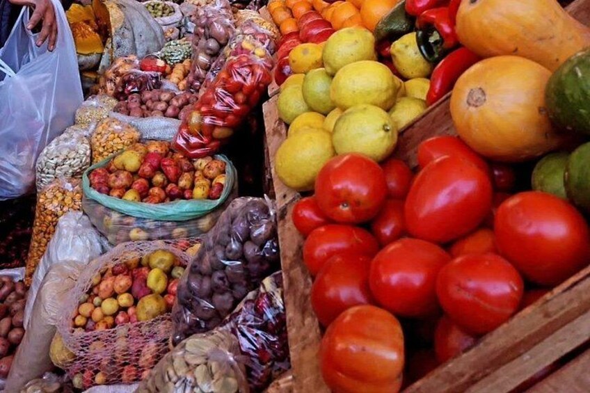 Ein Marktstand mit verschiedenen Früchten und Gemüsesorten, darunter Tomaten, Zitronen und Äpfel. 3