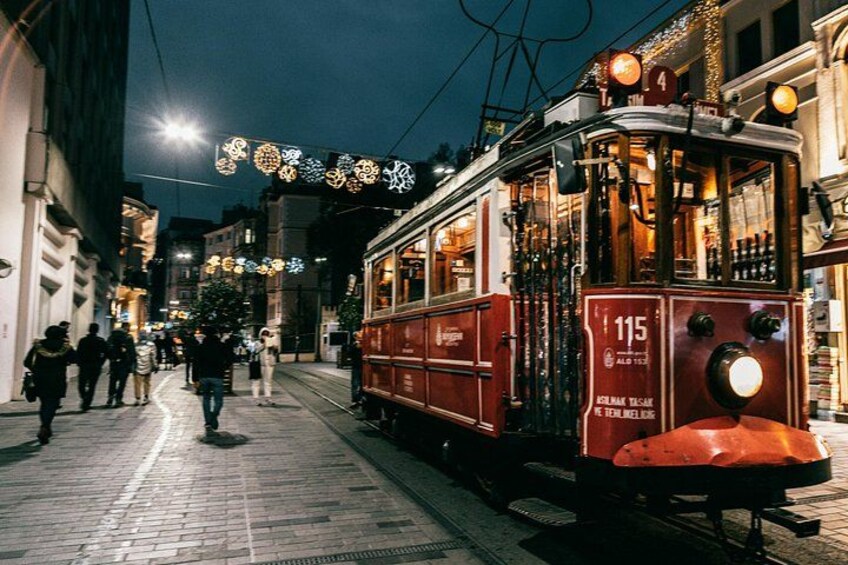 A red tram with the number 115 on a city street at night. 5