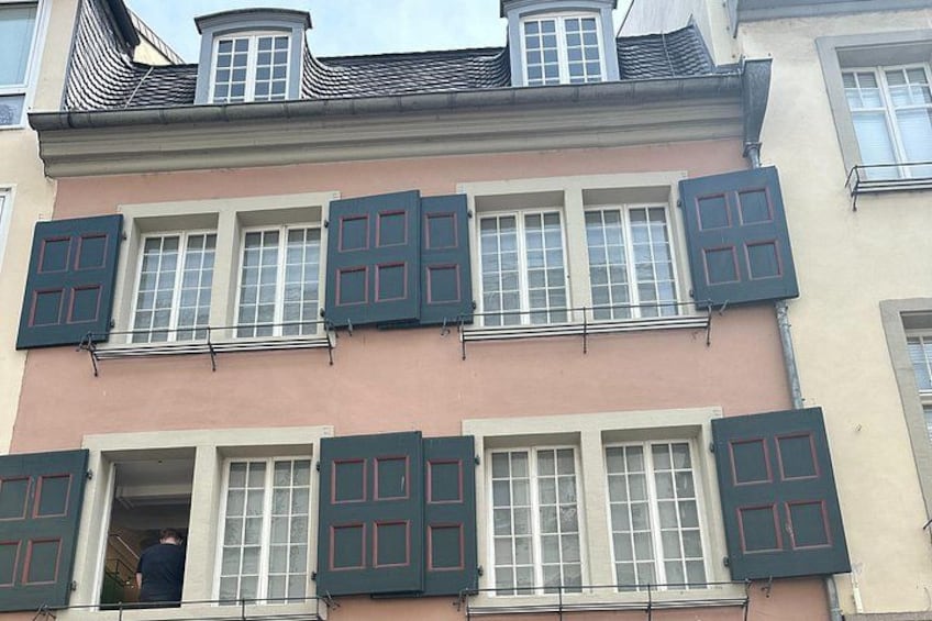 A multi-story building with a pink facade and dark shutters. 4
