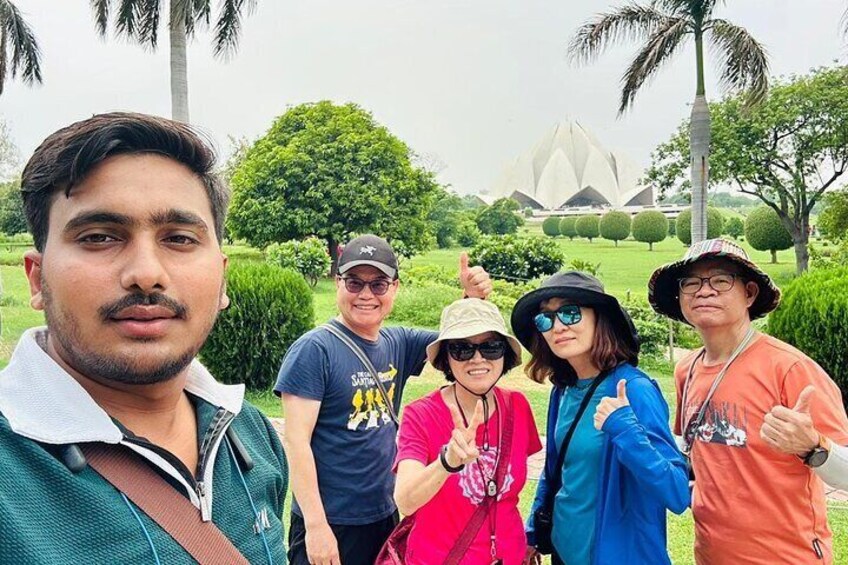 A group of people posing outdoors with a large, unique building in the background. 2