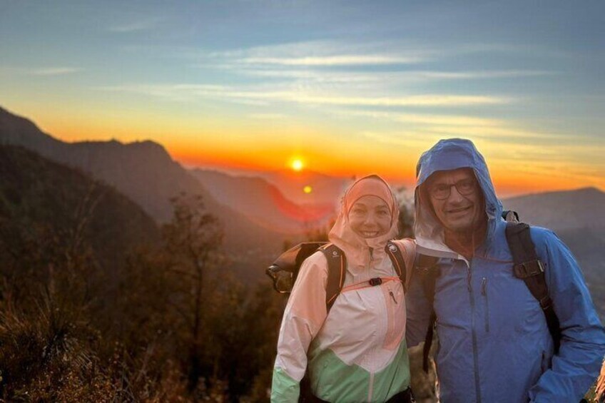 Two people hiking with a sunset in the background. 2
