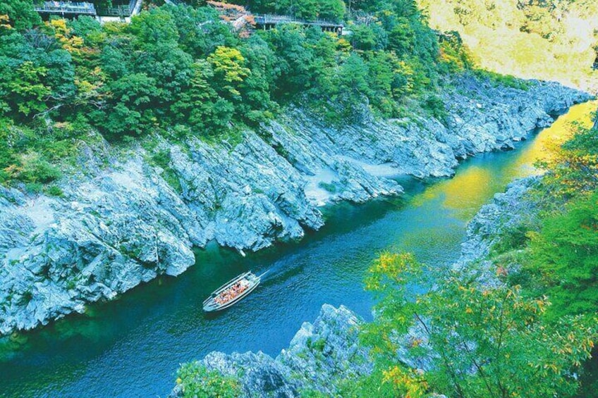 A river with a boat, surrounded by rocky cliffs and lush greenery. 5