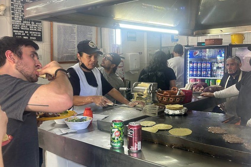 A kitchen with people cooking and serving food. 4