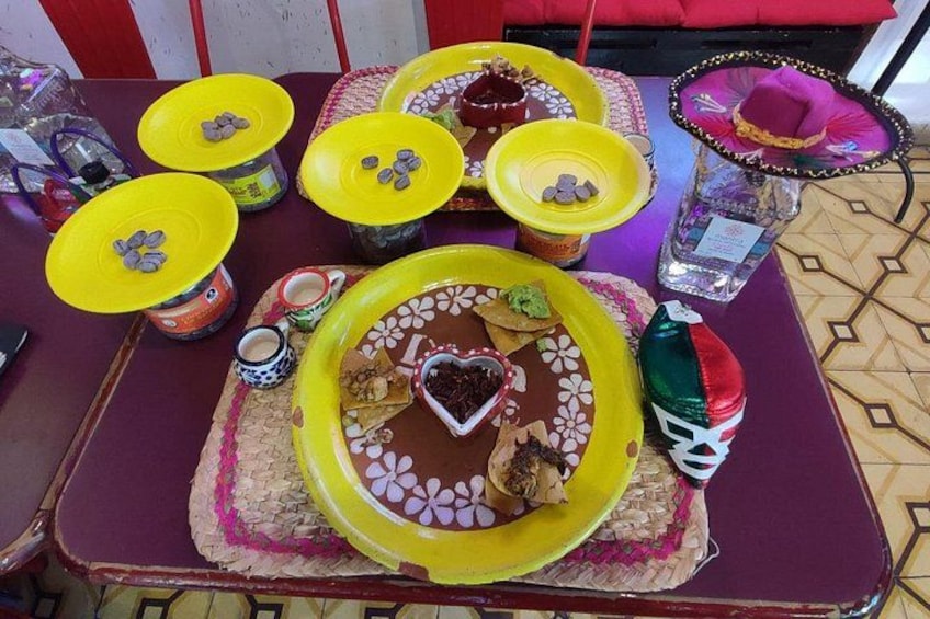 A table with a large yellow plate, smaller yellow plates, a bottle, and a decorative sombrero. 5