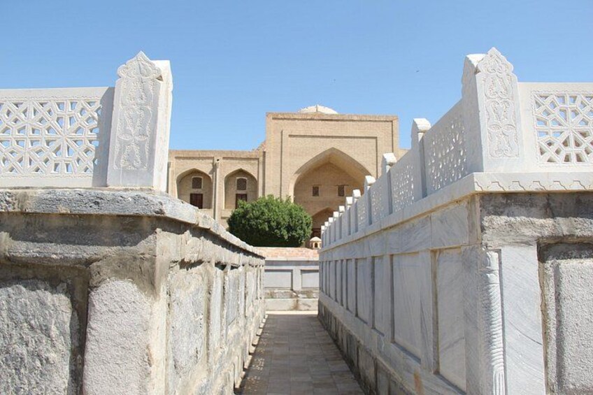 A pathway leading to a building with intricate white stone railings and a clear blue sky. 5