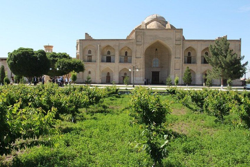 A large, historic building with a dome and arched windows, surrounded by a well-maintained garden with various plants. 3