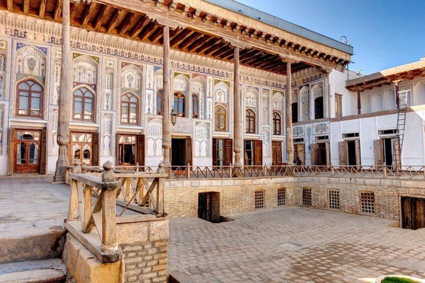 A courtyard with a traditional building featuring intricate tile work and wooden beams. 2