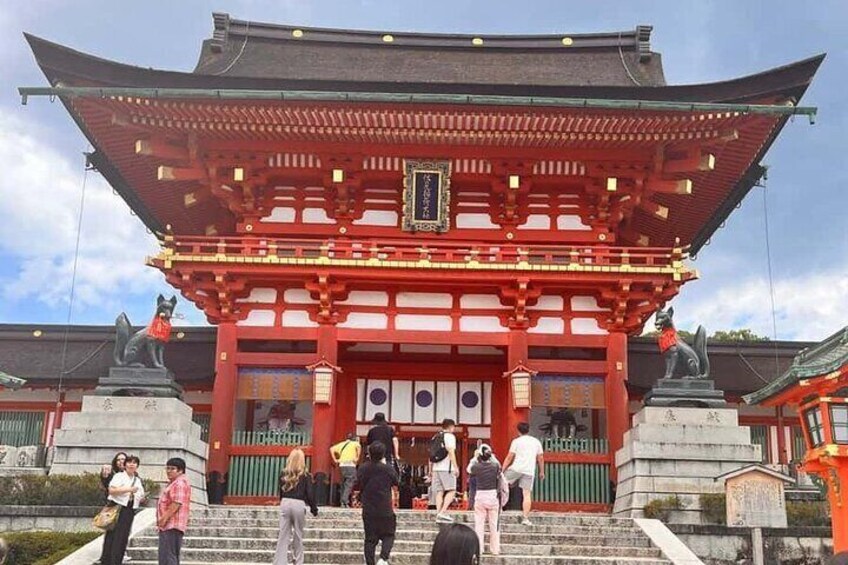 A traditional Japanese temple with a red torii gate, stone statues, and visitors. 5