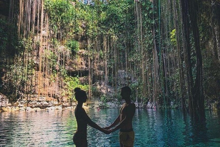 Two people holding hands in a forested area with a water body. 4