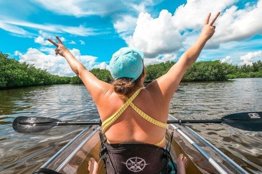 A person kayaking on a river with greenery on the banks. 1