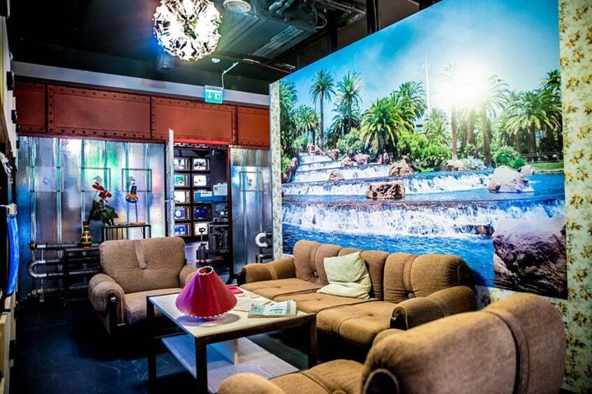 A lounge area with a large mural of a waterfall, comfortable seating, and a bookshelf. 3