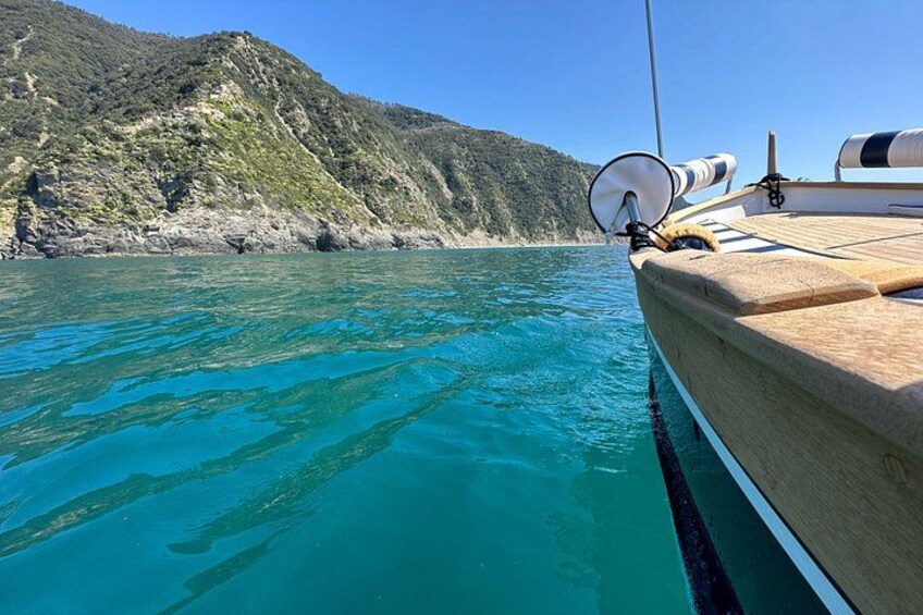 A boat on turquoise water with a rocky coastline and hills in the background. 4