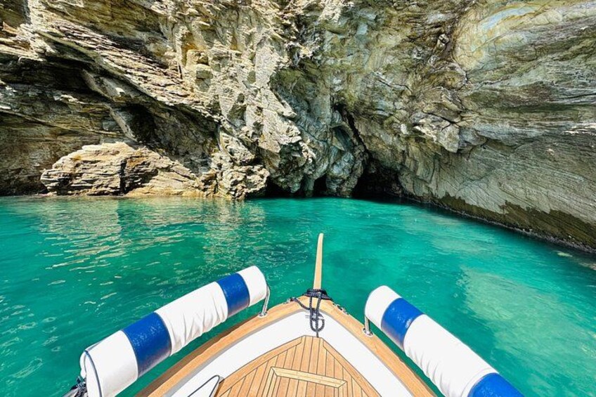 A boat in a turquoise sea with rocky cliffs. 3