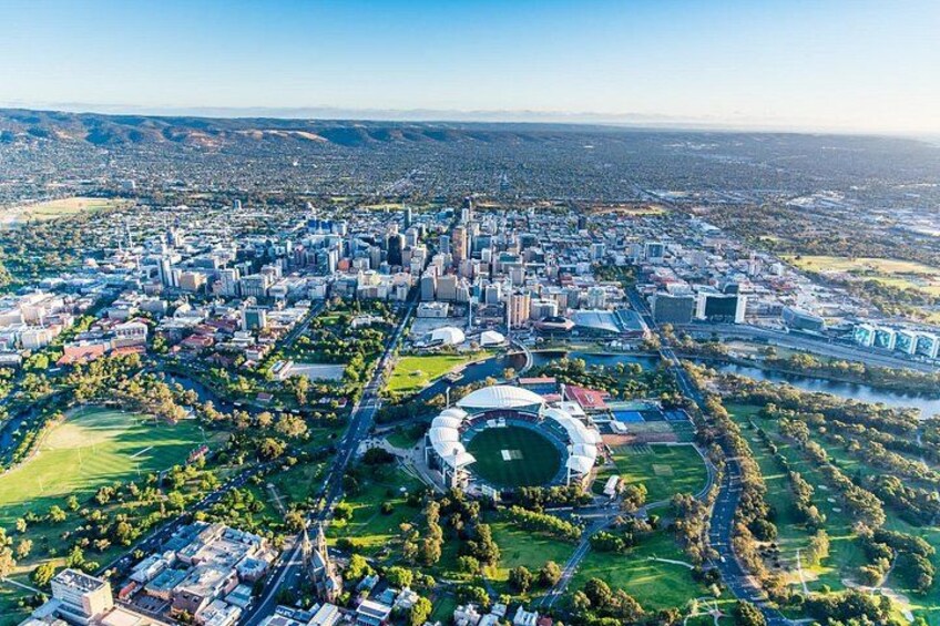 An aerial view of a city with a large stadium, dense urban area, and surrounding greenery. 3