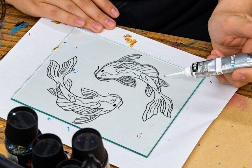 A person drawing fish on a paper with a glue bottle. 2