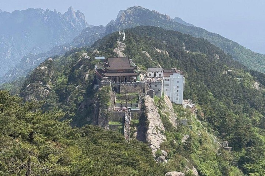 A temple complex on a mountain with traditional architecture, surrounded by lush greenery and rocky terrain. 4