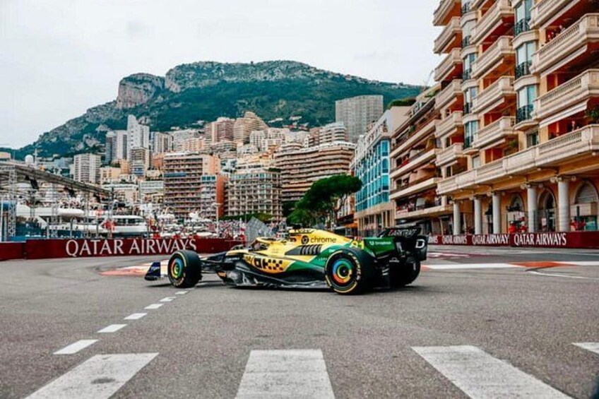Ein Formel-1-Rennwagen auf einer Rennstrecke vor einer Skyline und Bergen im Hintergrund. 2