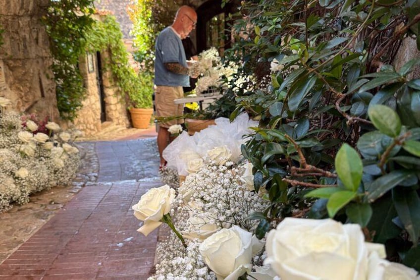 Un giardino con rose bianche, un vialetto in mattoni e una persona che si occupa dei fiori. 3