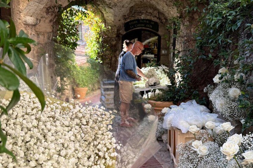 Una persona arreglando flores en un jardín con un arco rústico de piedra. 4