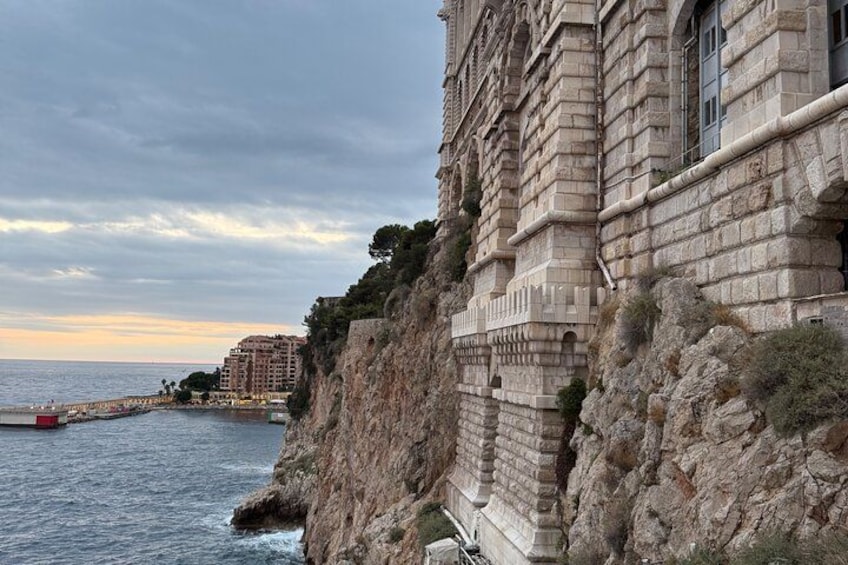 Un edificio sul lungomare con una scogliera rocciosa, un molo e un tramonto sullo sfondo. 5