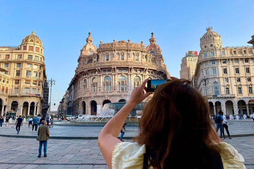 Un edificio histórico con arquitectura ornamental, una fuente y gente caminando. 5