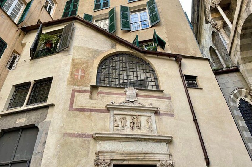 Fachada de edificio con un gran ventanal arqueado, una estatua y un símbolo de cruz. 4