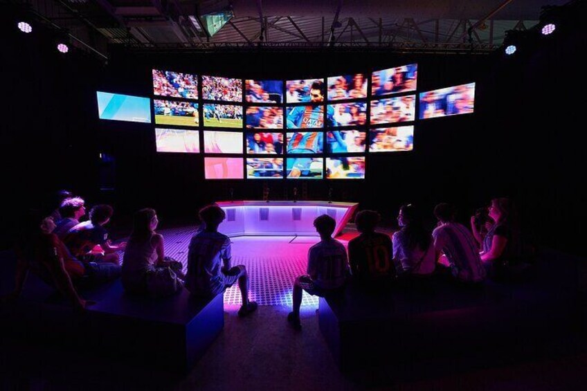 A group of people seated in a dimly lit room with multiple screens displaying sports events. 5