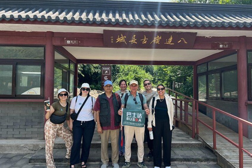 A group of people standing in front of a traditional building with a tiled roof and a signboard. 2