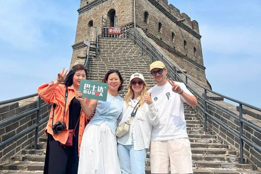 A group of people posing in front of a historic stone tower with a staircase. 2