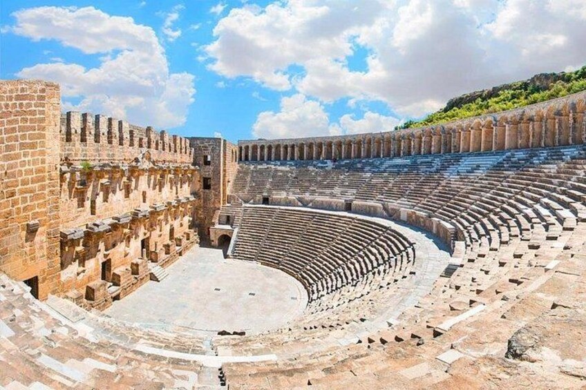 An ancient amphitheater with stone seating and a central stage. 1