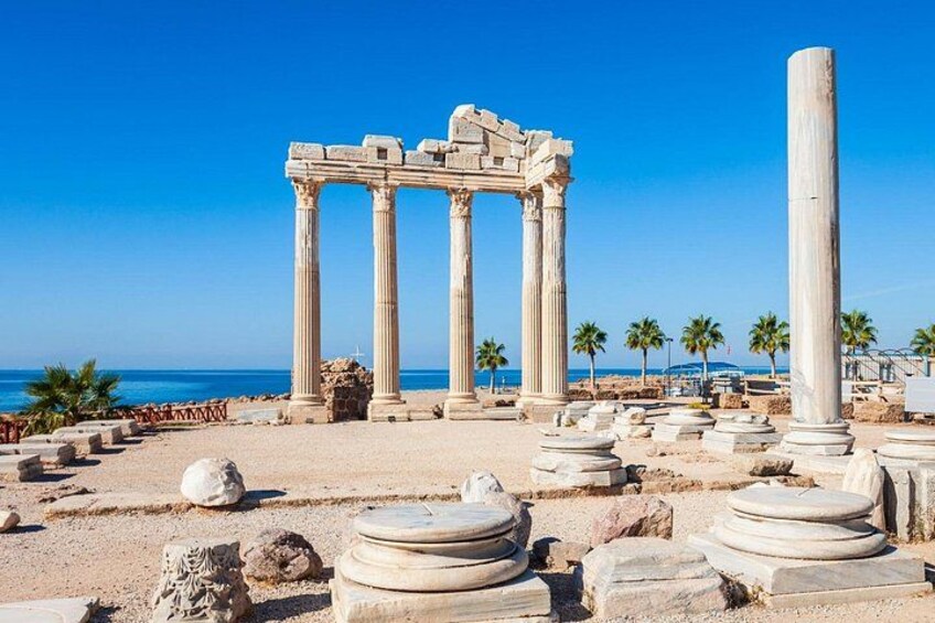 Ancient ruins with columns and scattered stones near a beach. 2