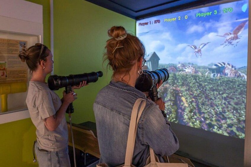 Two people using telescopes to observe a projected game on a screen. 5