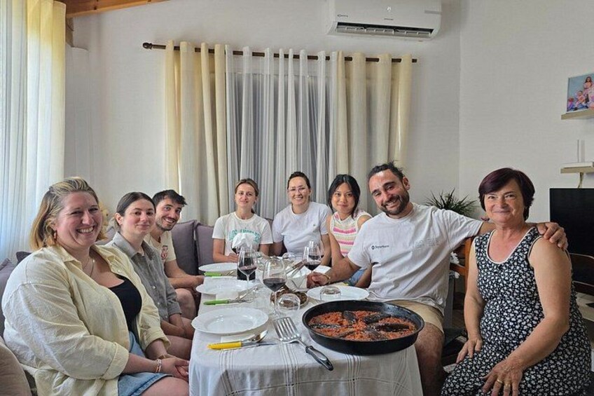 A group of people seated around a dining table with a meal, in a room with curtains and a television. 4